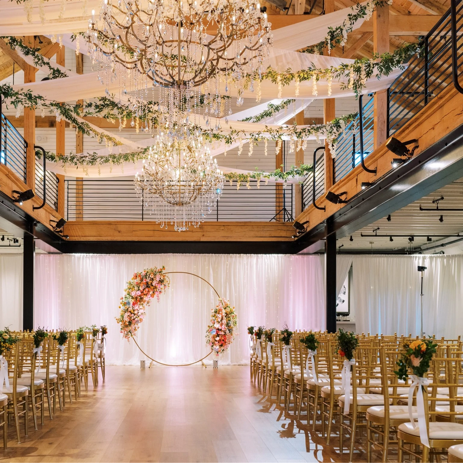 A wedding ceremony venue indoors with chairs and decorated chandeliers