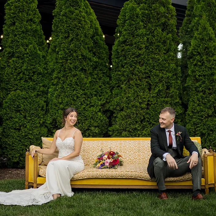 Bride and groom take a photo on a yellow counch outside of Brentsville Hall, Manassas, Virginia