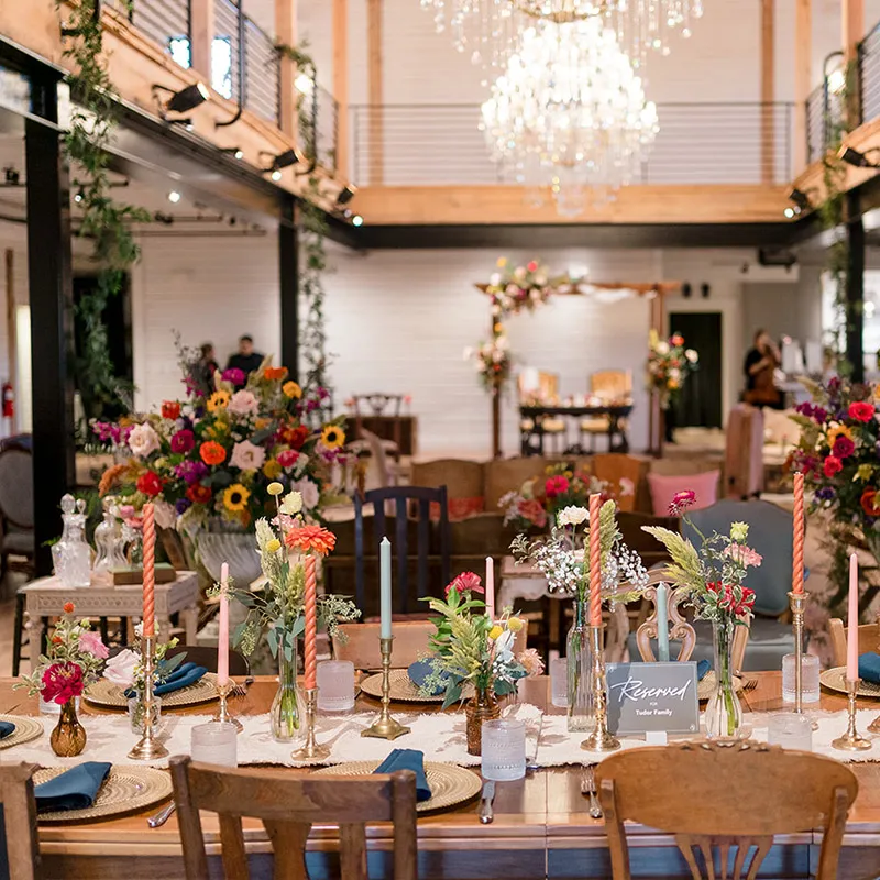 The guests' table ready for dinner with candles, flower bouquets, and place settings