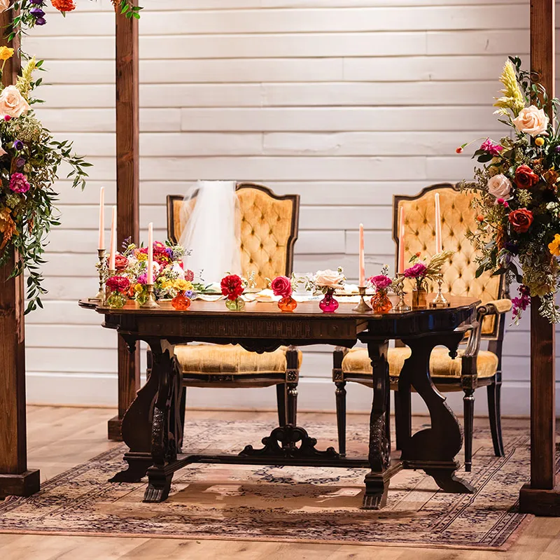 The bride and groom's table at the front of the room decorated with candles and cut flowers