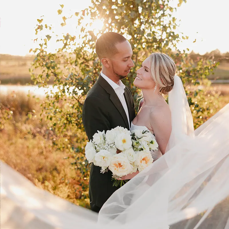 Bride and groom pose with a lovely bouquet as the sun sets on the beautiful landscape around Brentsville Hall in Northern Virginia